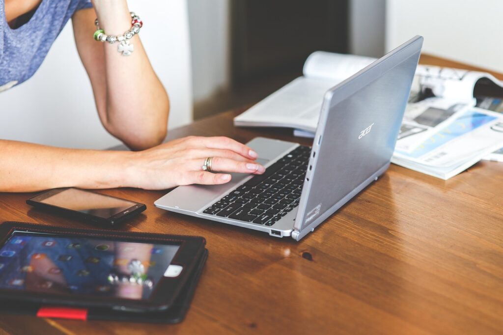 woman using laptop computer on desk surrounded with phone, tablet, and books or magazines. Symbolic of how we are, like these, used as God's tool