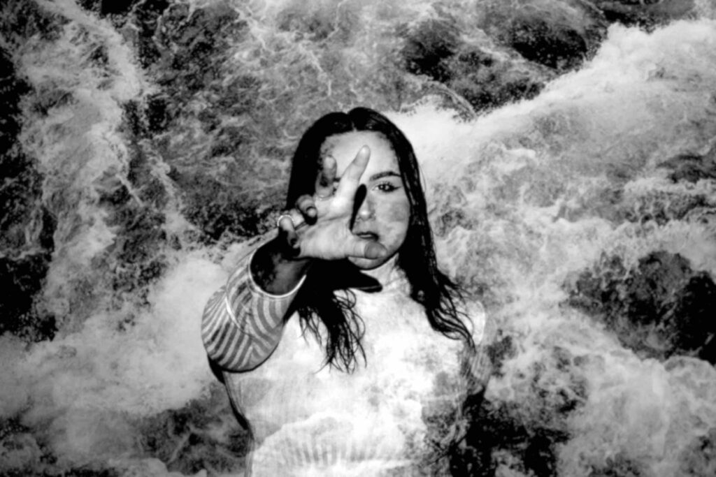 A black and white photo of a woman splashing in water with arm reaching out to her point of contact