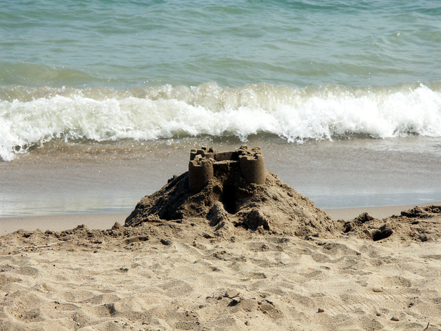 A sandcastle built with great ambitions and waves in the background.