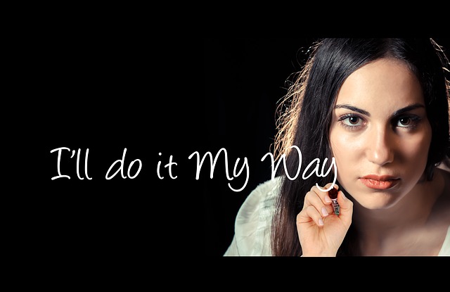 An assertive woman declaring her individuality by writing on clear surface 'I'll do it my way" while facing the viewer