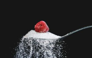raspberry resting on a spoonful of sugar
