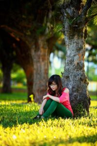 young woman sitting by tree
