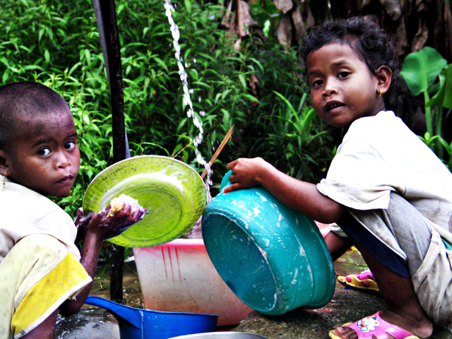 two indigenous children washing dishes