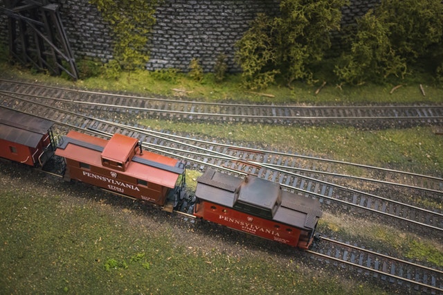 An overhead view of three red cabooses sitting on one of several train tracks including one that curves away from the others.
