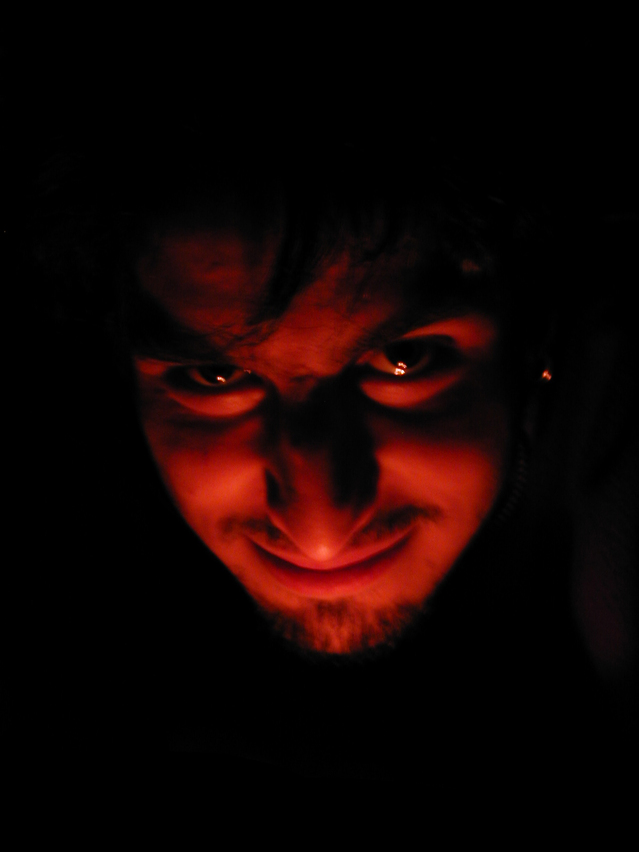 man with devil like appearance with red candlelight underneath face