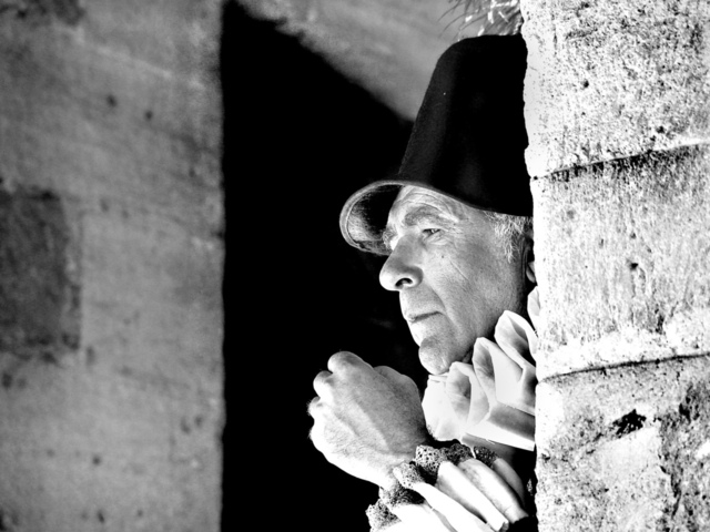 An older waiter in Elizabethan period dress looking outside from a doorway symbolizing how we are to be focused on Jesus