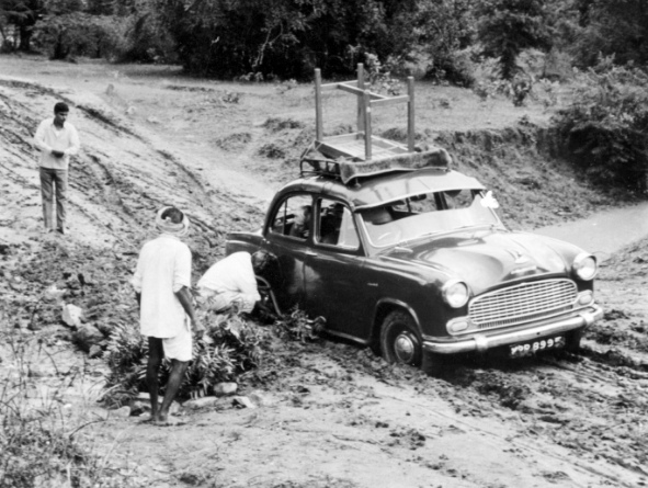 Black and white photo of an old car stuck in the mud