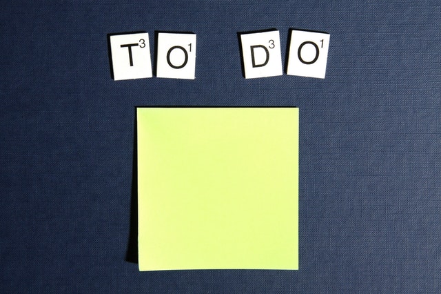 a yellow sticky note with the letters from a Scrabble game above spelling the words 'to' & 'do'