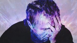man with head down, eyes closed and hand over face
