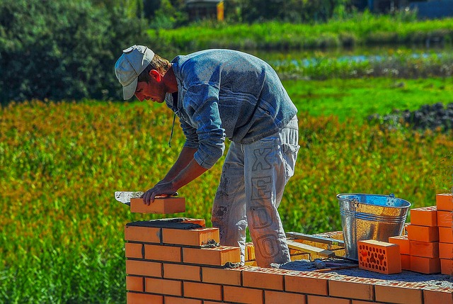 Man bent over laying bricks