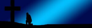 graphic of blue background with a silhouette of person kneeling at a cross