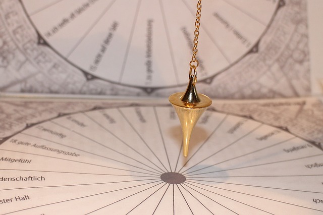 A photo of a gold pendulum swinging on a printed diagram