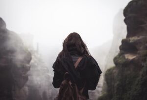 backside of woman hiking on heavy fog path