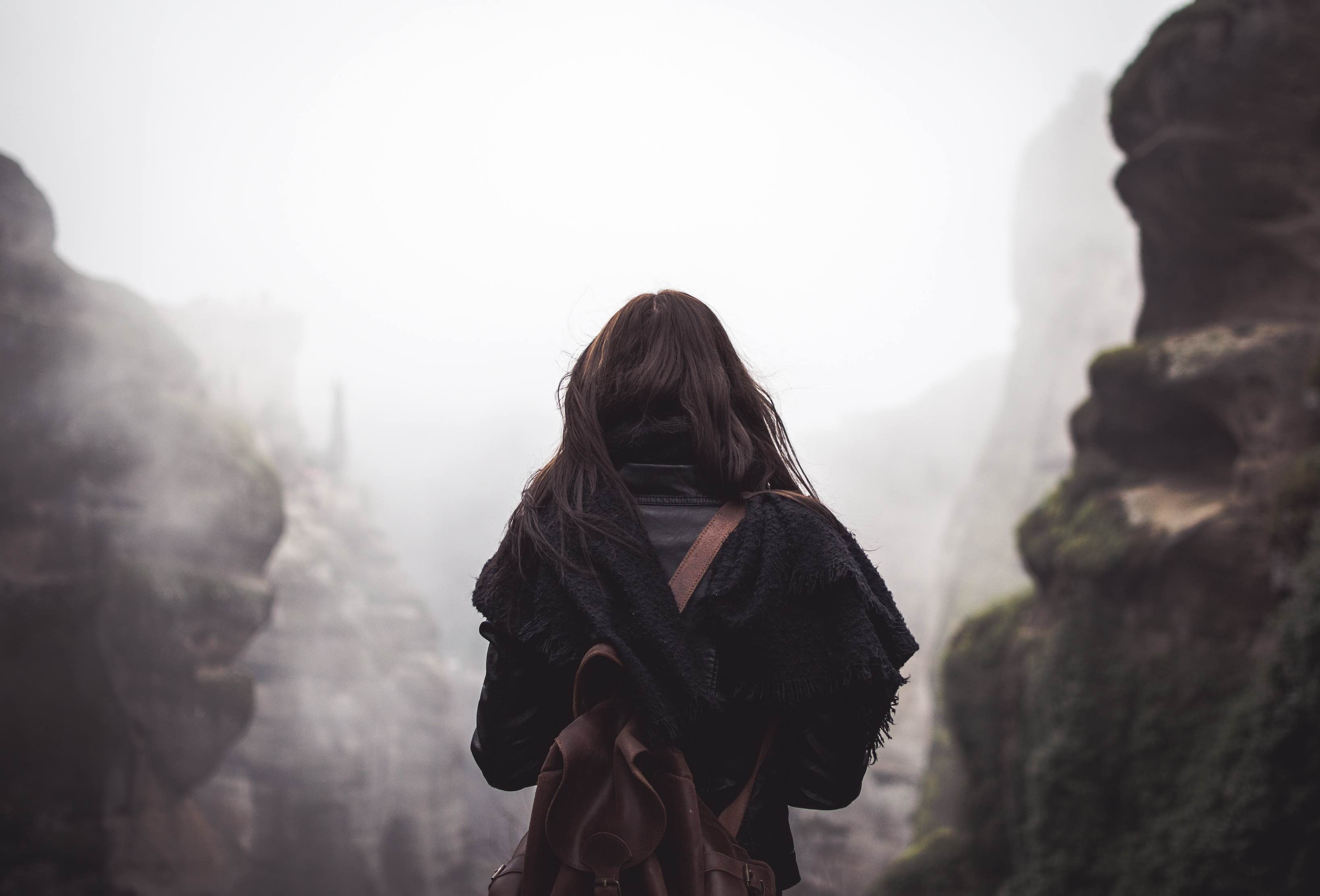 backside of woman hiking on heavy fog path resembling one who is led by God.