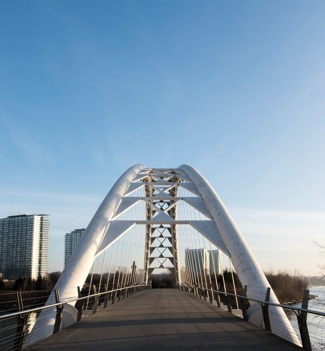 A modern steel arch suspension pedestrian bridge that feels good to cross.