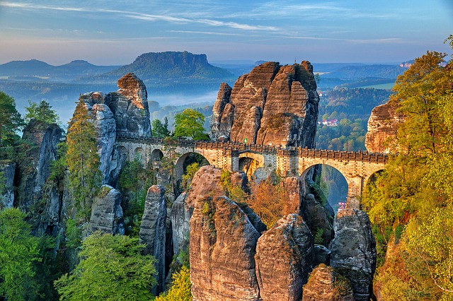 A photo of Bastei bridge, a stone arch crossing through a steep mountainous region.