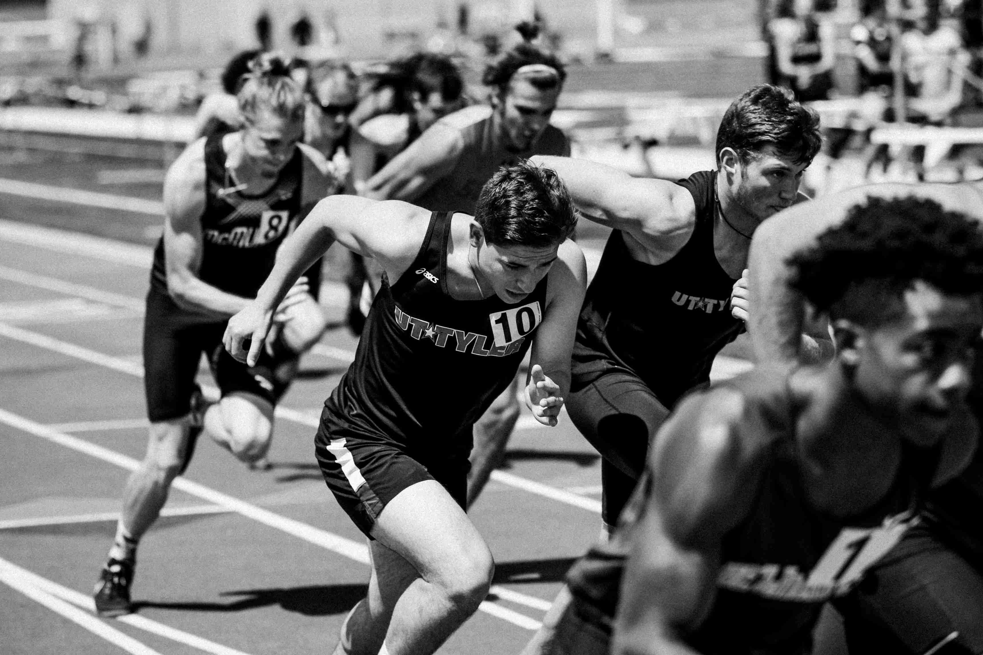 A black and white photo of several runners racing on a track