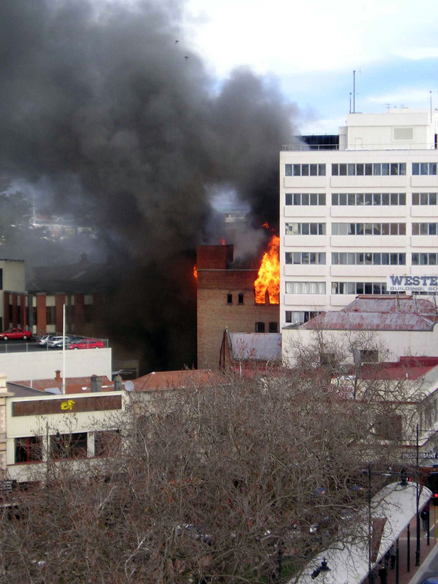 photo of flames and smoke coming from a small building in a city