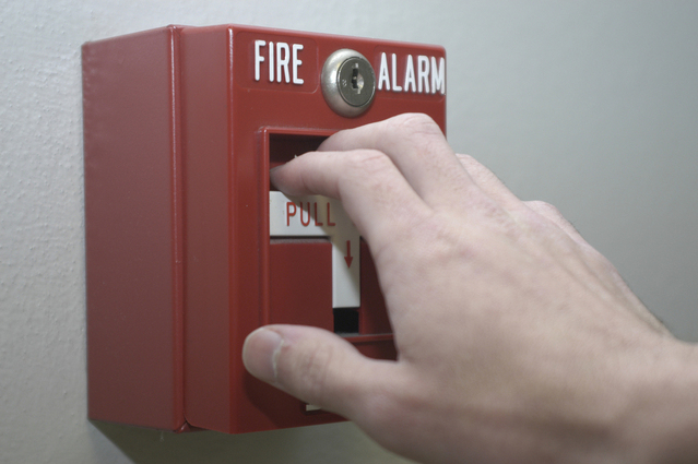 Photo of believing in the unseen hand over fire alarm pull box symbolic of one believing in the unseen fire