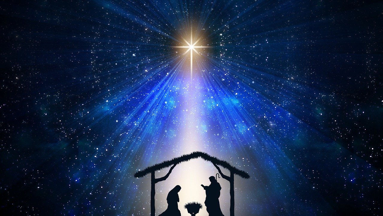A graphical image of a manger scene with a star above in a blue-black starry night scene.