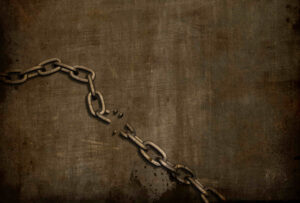 A monochrome image of a broken section of chain on a brown textured background