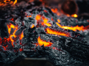 Glowing embers in black ashes from a large fire