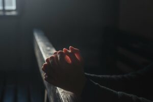 Hands in prayer with soft light streaming in from a window