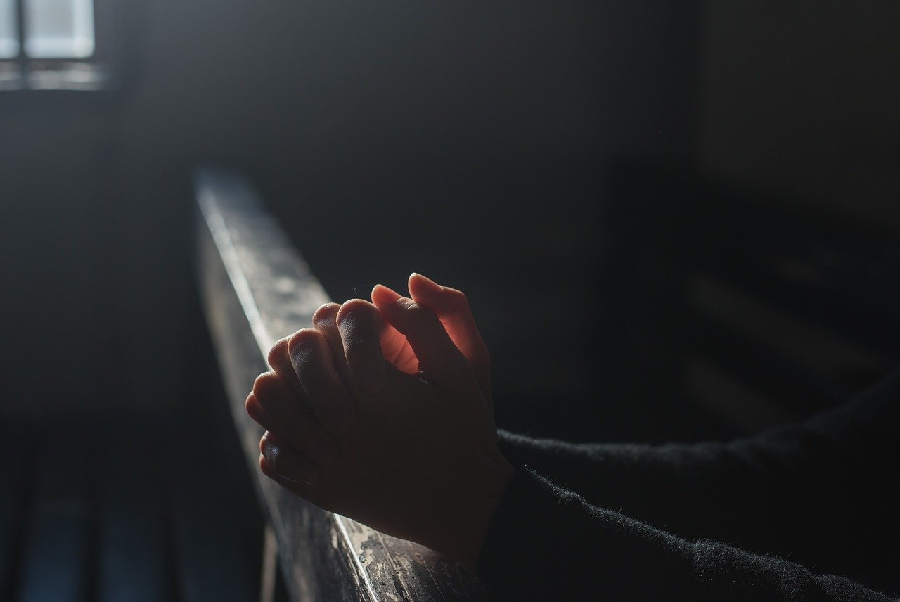 Hands in position of prayer in soft light from nearby window