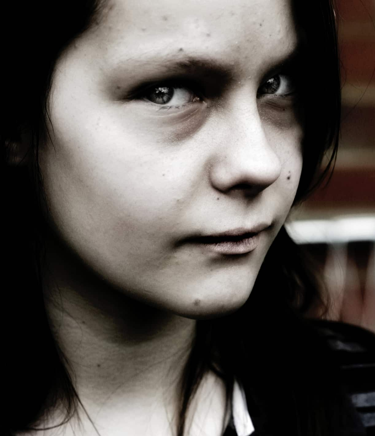 Younger woman facing camera with head turned slightly and expression of warning or evil in eyes