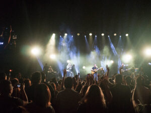 Contemporary worship service with people standing and raising arms in the air
