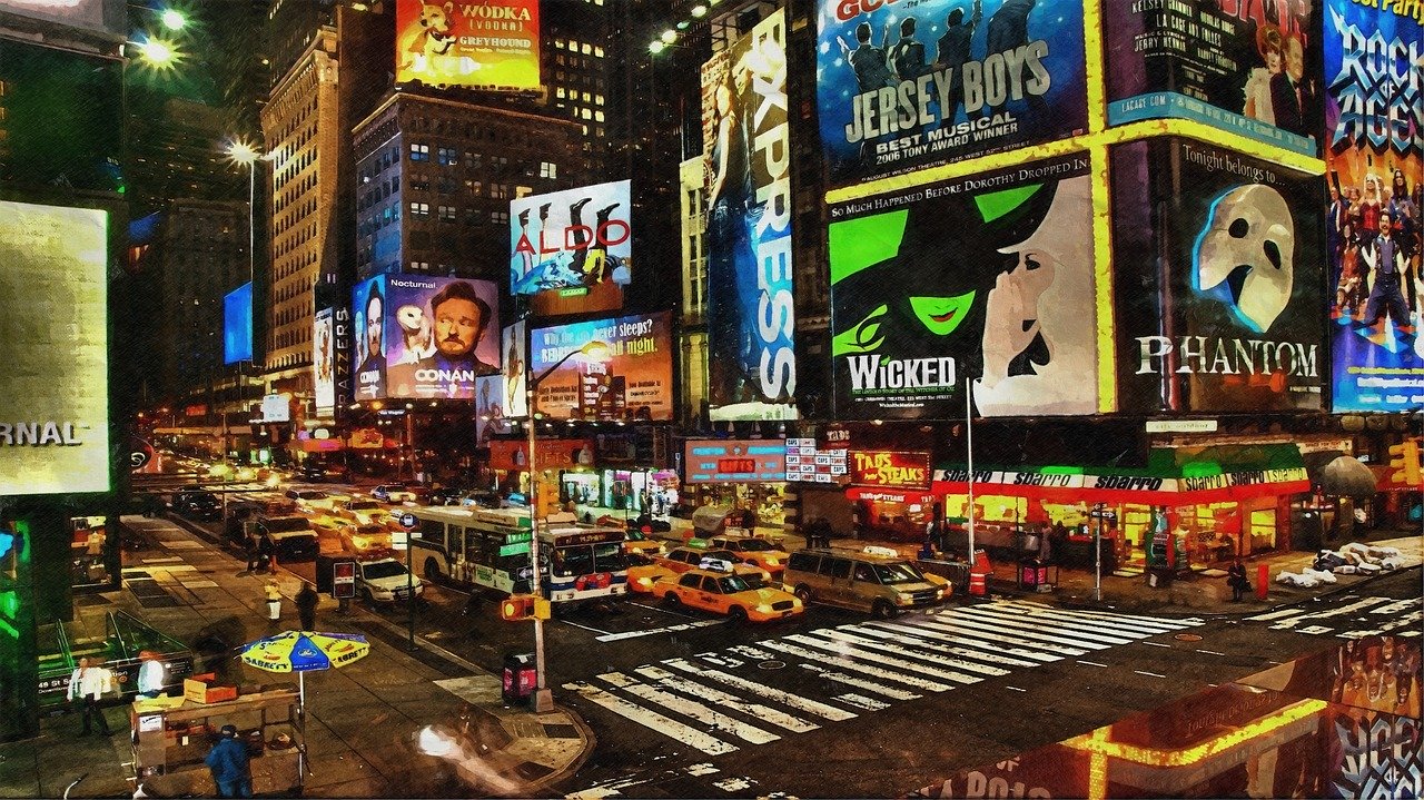 A colorful intersection decorated with billboards and many taxis on the street at night at Times Square in New York City