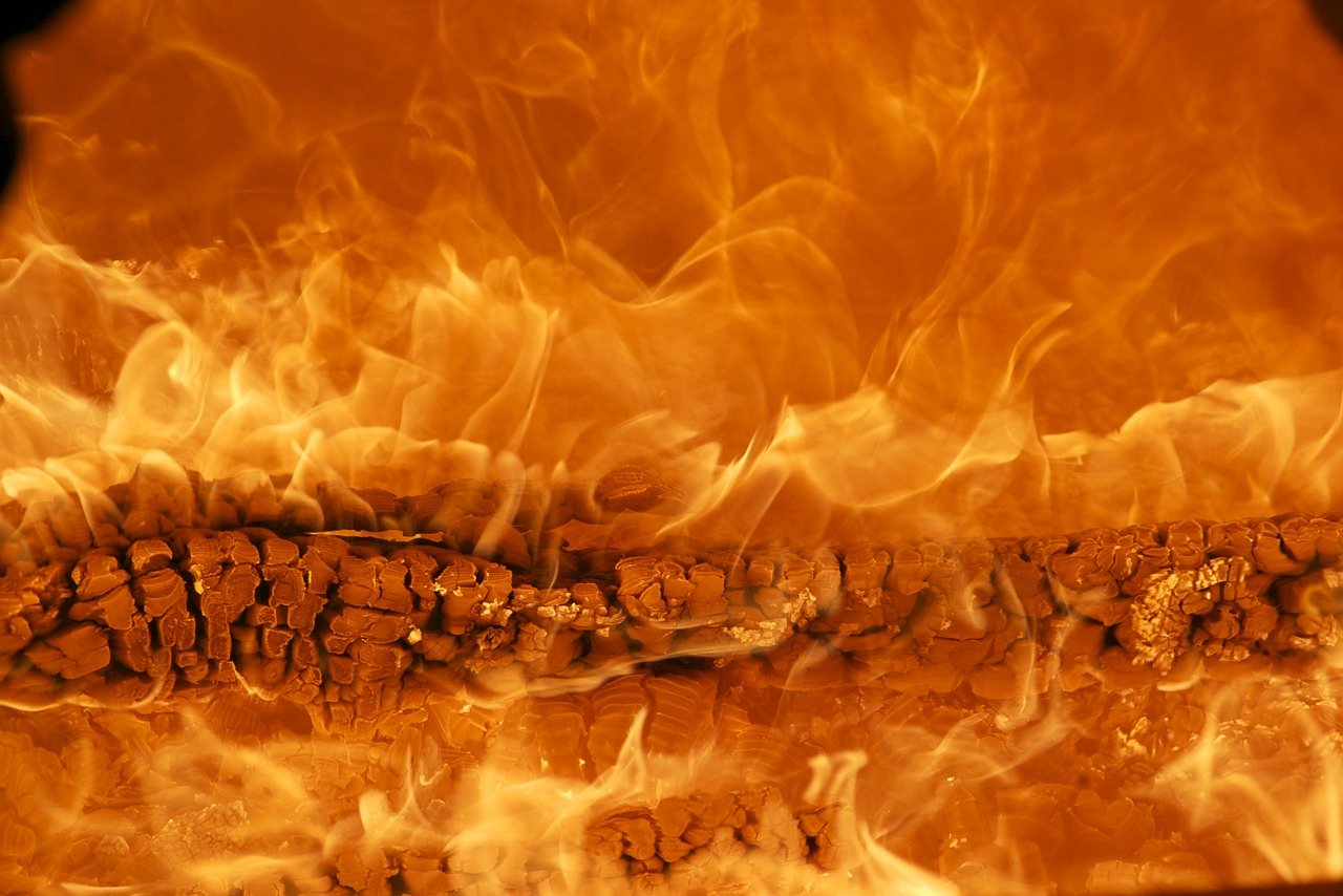 A photo full of intense flames like those of hell emanating from a burning log in the center of the picture
