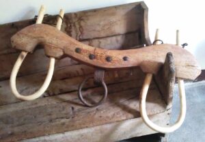 A old wood yoke displayed lying across an antique wood bench in a room