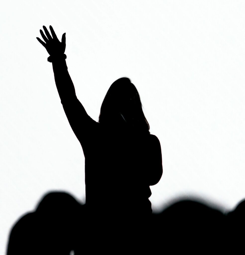 A silhouette of a woman with a hand raised in front of a white background