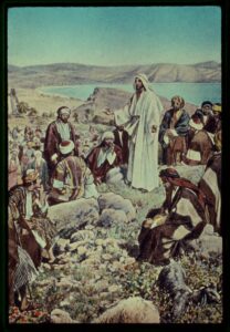 A painting of Jesus standing on a rocky elevated portion of a mountainous region with his arms outstretched speaking to a group of Middle Eastern men during the daytime