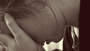 Closeup sepia style photo of young woman with head in hands and crying