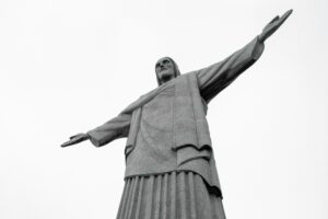 Looking upward at a large stone sculpture of Jesus Christ with His arms outstretched in the air