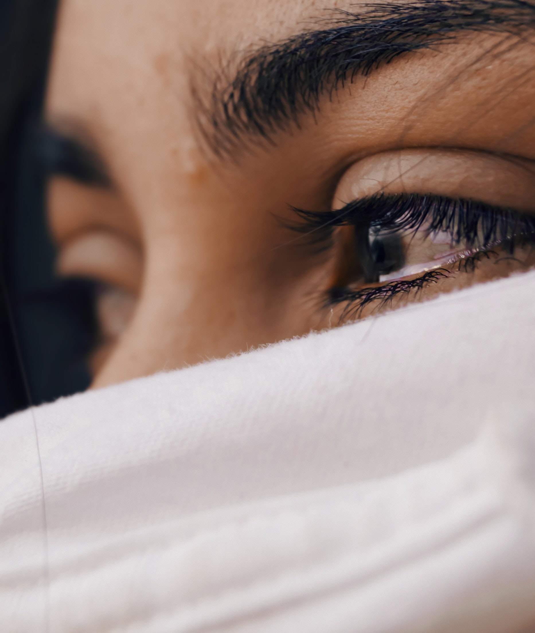 A close up photo of a woman's eyes and forehead with a white cloth veiling the rest of her face
