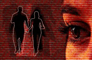 A graphical image of a brick wall with white outlines of a silhouette of a male and female walking together while holding hands and a superimposed image of a part of a woman's face with the eye and eyebrow portion displayed prominently