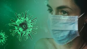 A combined photo of an enlarged image of coronavirus and the headshot of a woman wearing a disposable face mask