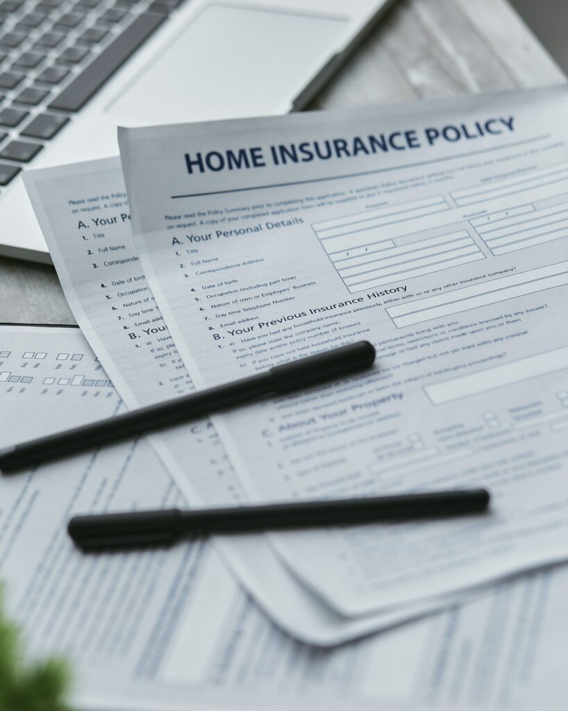 A photo of several pages of a blank application for home insurance and two black pens resting on top.