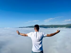 F-man-outstretched-arms-overlooking-cloud-tops-ilyas-onar--0WAxcFb5ok-unsplash(https:::unsplash.com:photos:-0WAxcFb5ok)