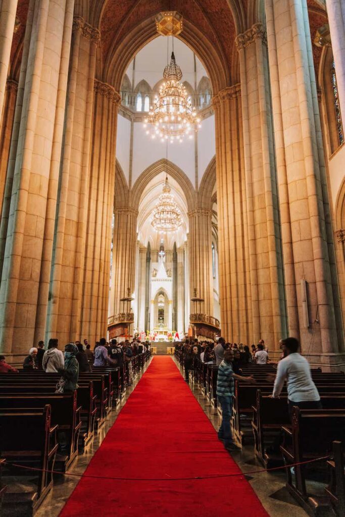 A large cathedral of a religion with many people standing among the pews.