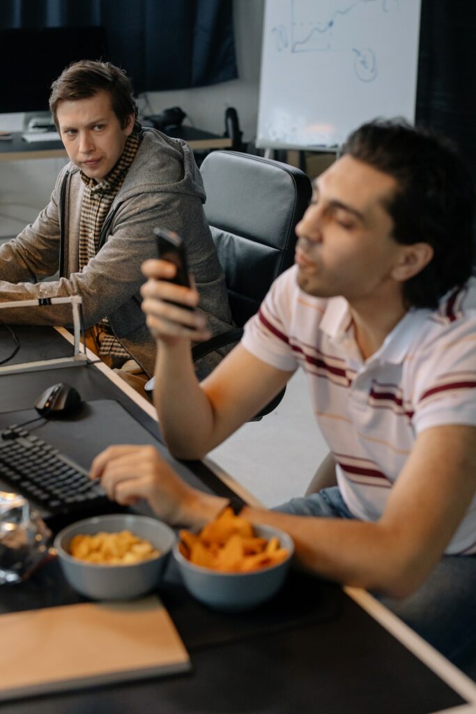 A man sitting at a workstation displaying envy for another nearby