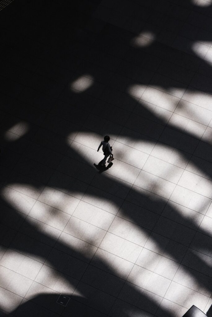 When not under God's shadow one is vulnerable to attack just like this person walking between shadows on a large walkway.
