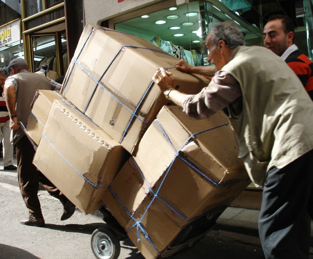 A cart of boxes being hauled down a walk symbolizing the need to cut the burdens of the flesh keeping us weak with God