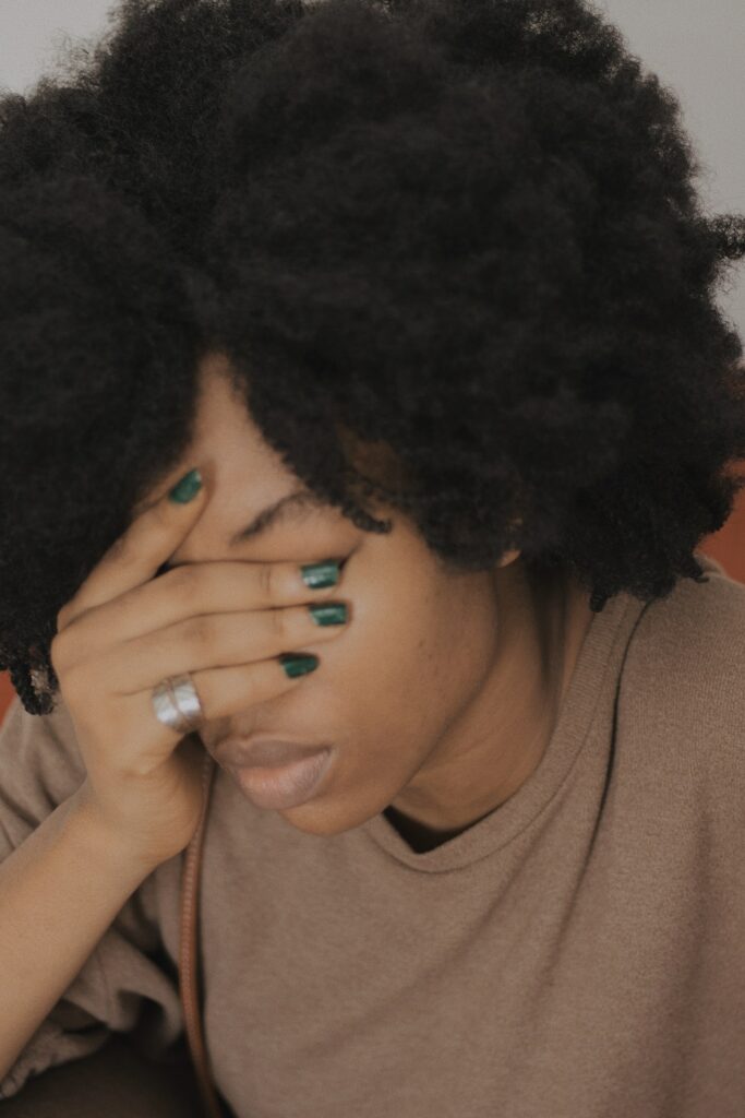 A woman seated looking down with her hand over her face with a depressed appearance illustrative of what happens when you are looking to yourself for the solution