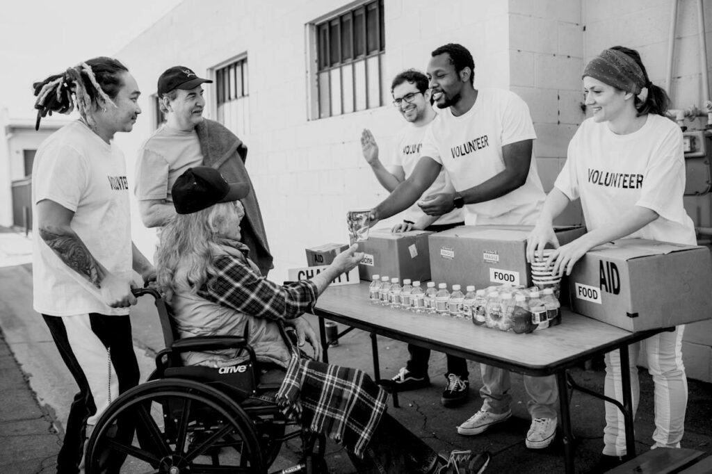 A group of volunteers doing good works in giving aid to an elderly person
