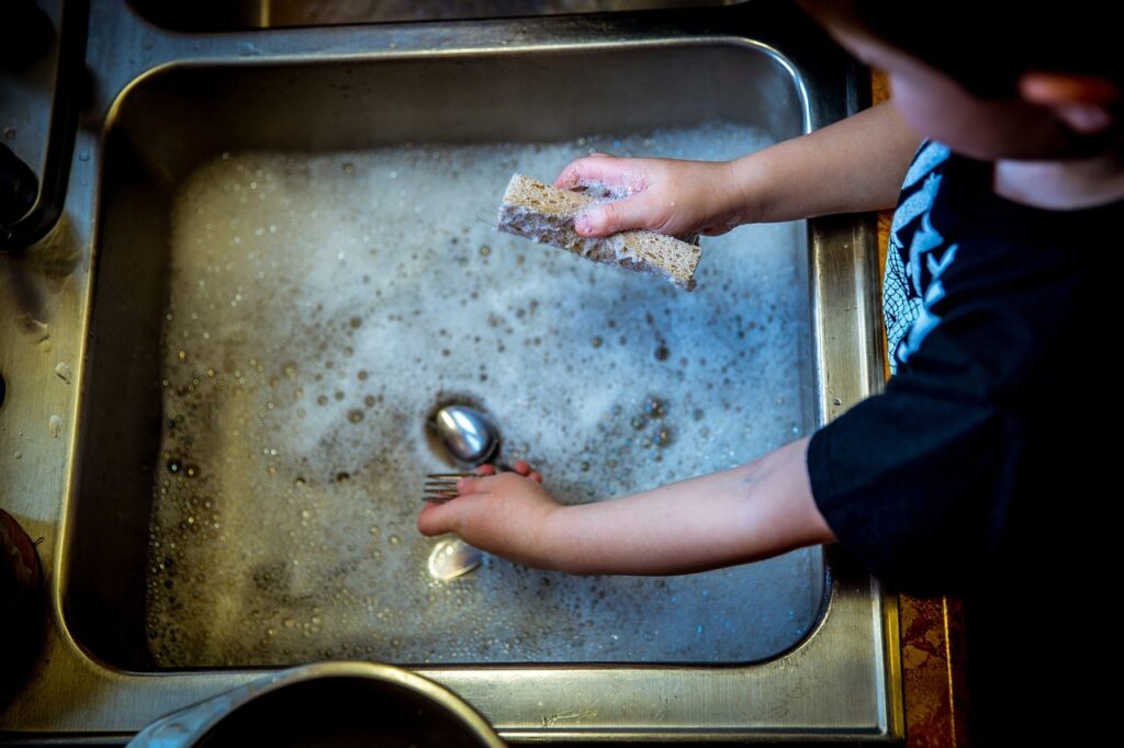 A boy scrubbing items in a sink demonstrating the results when we do something by our own efforts.