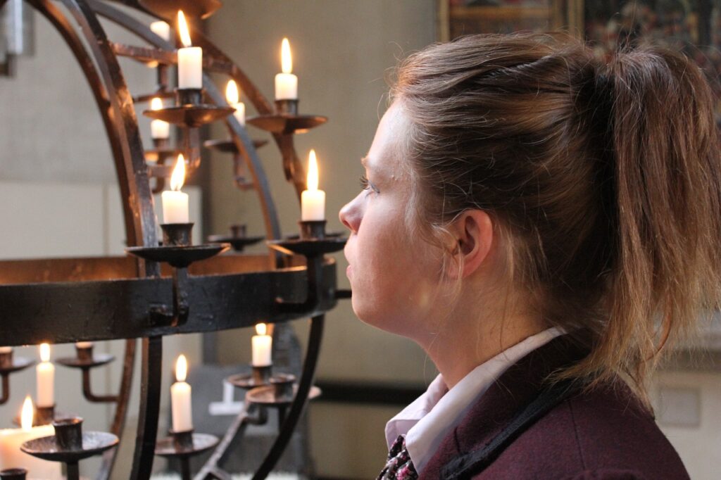 A woman looking a sculpture holding lit candles symbolizing whether we trust in God or in works we do ourselves
